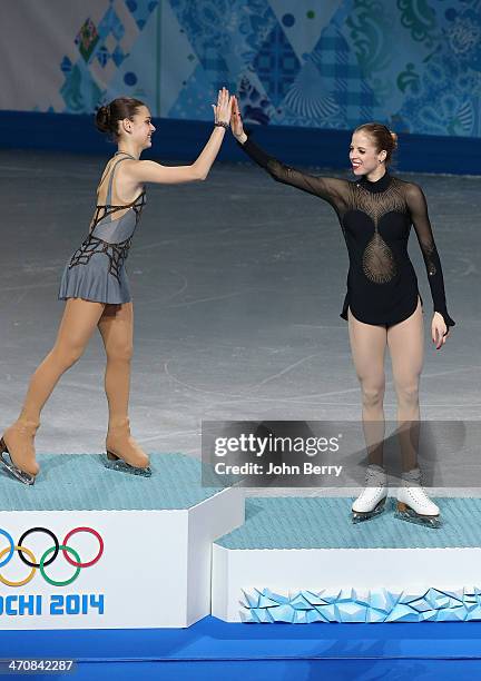 Gold medalist Adelina Sotnikova of Russia gives a high five to bronze medalist Carolina Kostner of Italy on the podium during the flower ceremony for...