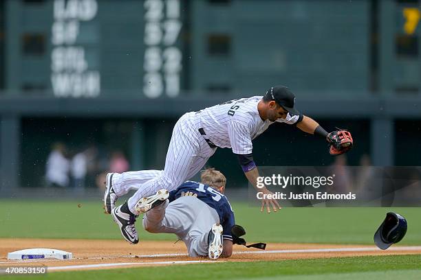 First baseman Daniel Descalso of the Colorado Rockies tumbles over Cory Spangenberg of the San Diego Padres after Spangenberg reached on an infield...