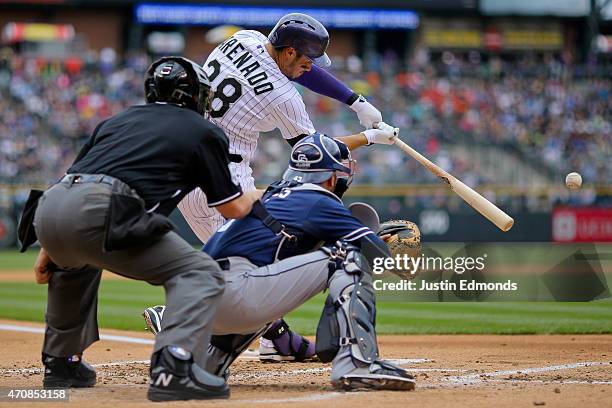 Nolan Arenado of the Colorado Rockies hits an infield single during the first inning as catcher Wil Nieves of the San Diego Padres and home plate...