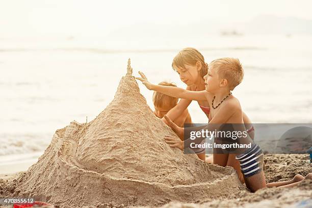 kids building a giant sandcastle - sandcastle stock pictures, royalty-free photos & images