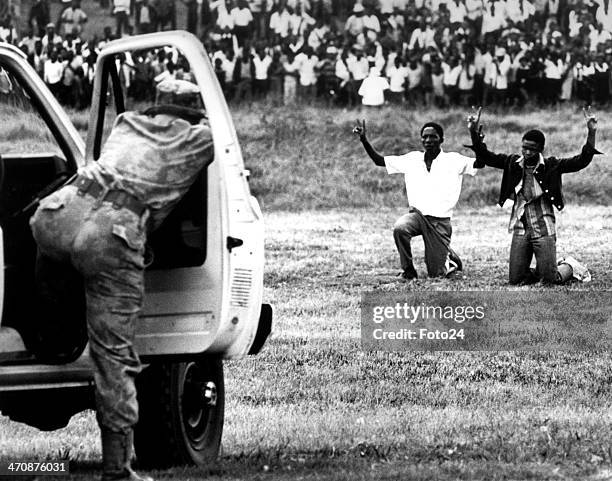 Soweto youths kneeling in front of the police holding their hands in the air showing the peace signon June 16 in Soweto, South Africa.