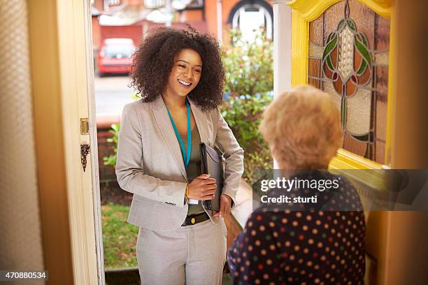 saleswoman introduces herself to senior woman at the door - dörrförsäljare bildbanksfoton och bilder