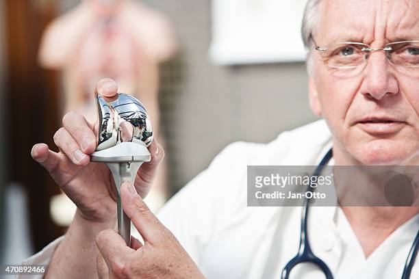 mature doctor presenting total knee prosthesis - orthopedic surgery stock pictures, royalty-free photos & images