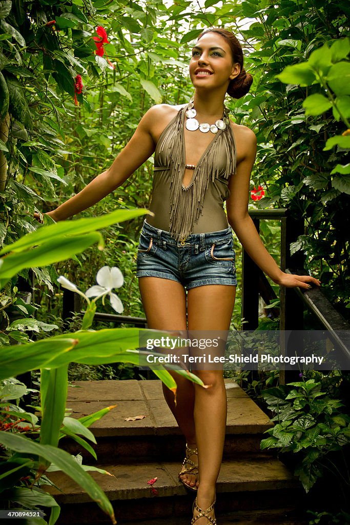 Portrait of young woman walking down steps through foliage