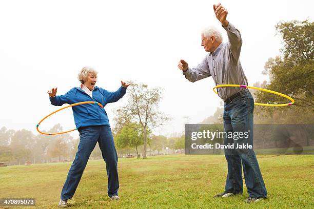 husband and wife playing hula hoop in the park - jogar ao arco imagens e fotografias de stock