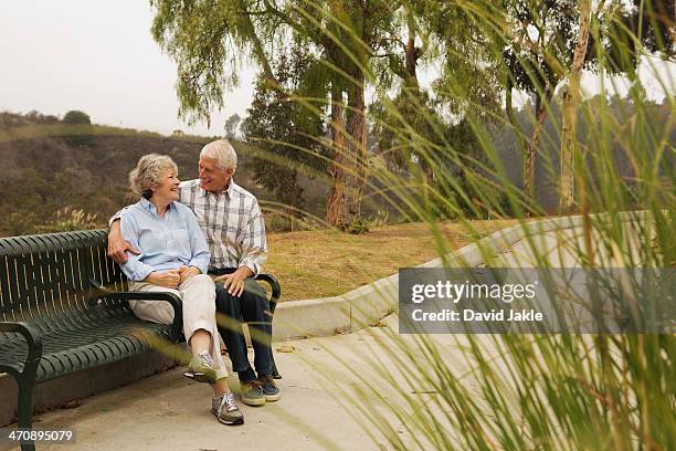 husband and wife chatting lovingly on park bench - woman smiling facing down stock pictures, royalty-free photos & images