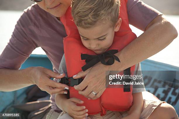 mother fastening son's life jacket - life jacket photos foto e immagini stock