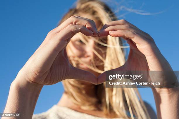 young woman making heart sign with hands, breezy point, queens, new york, usa - hands in the air heart stock-fotos und bilder