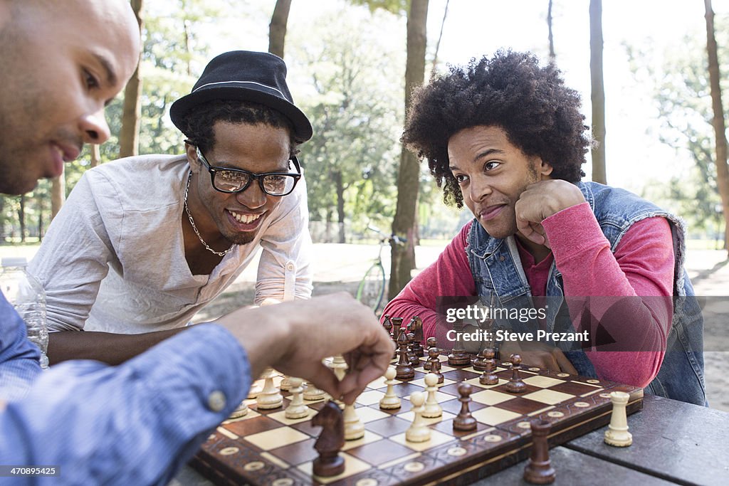 Three young men playing chess in park