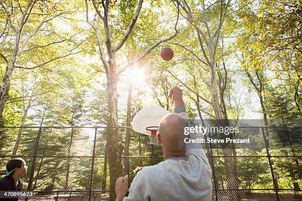 young man throwing basketball towards goal - 2013 usa basketball men stock pictures, royalty-free photos & images