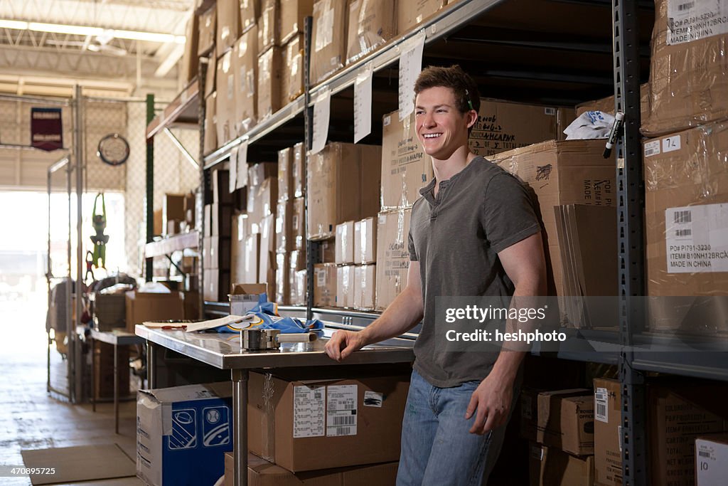 Worker standing in warehouse, leaning against shelving