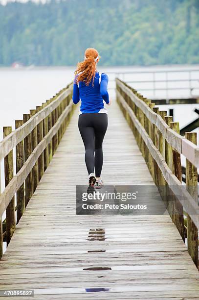 teenage girl jogging on pier, bainbridge island, washington, usa - girls in leggings stock-fotos und bilder