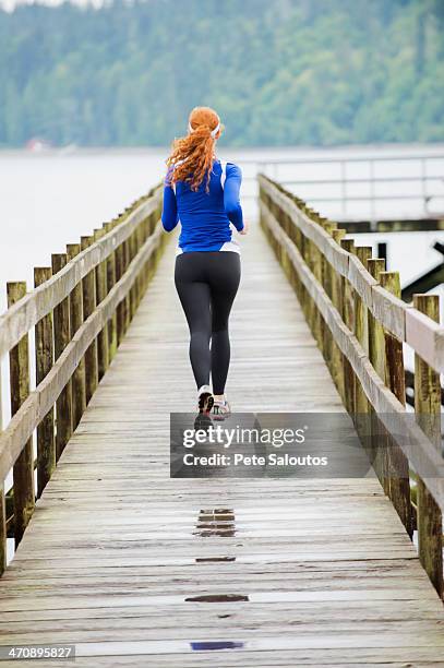 teenage girl jogging on pier, bainbridge island, washington, usa - girls in leggings stockfoto's en -beelden