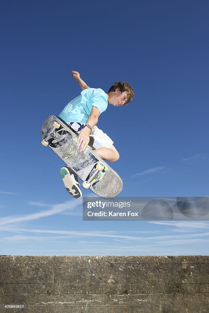 Teenage boy mid air on skateboard