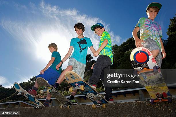 portrait of four boys on skateboards - kids athletic pants stock pictures, royalty-free photos & images