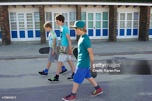 three boys carrying skateboards - teen boy shorts stock pictures, royalty-free photos & images