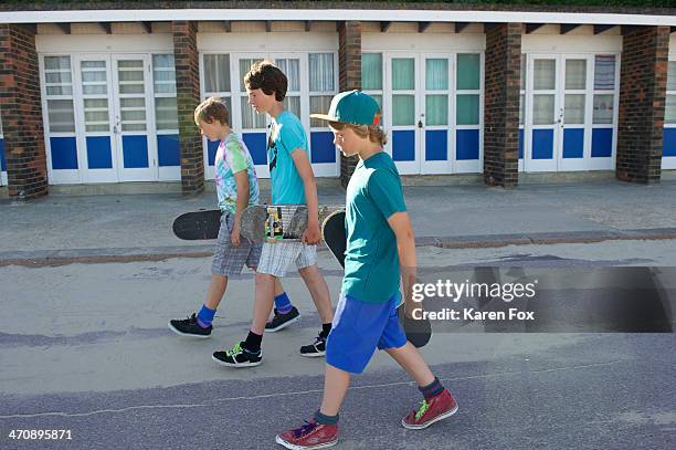 three boys carrying skateboards - teen boy shorts imagens e fotografias de stock