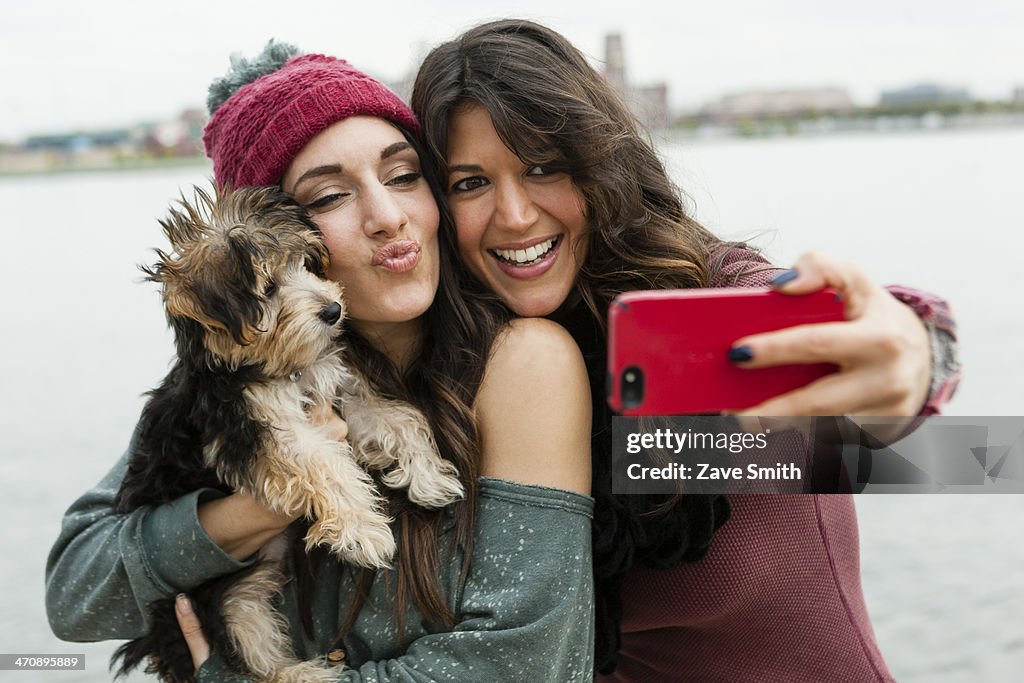 Friends holding pet dog for photograph