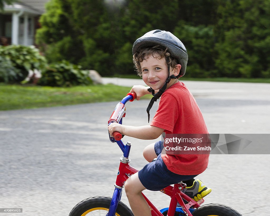 Portrait of young boy riding bicycle on driveway