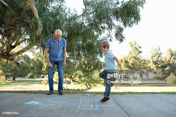 boy on hopscotch, grandfather watching - hopscotch stock-fotos und bilder