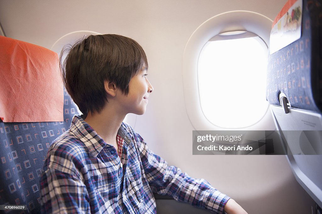 Boy looking out of window on aeroplane