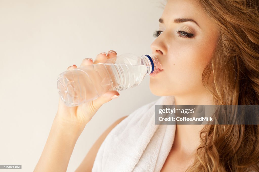 Beautiful woman with mineral water and towel