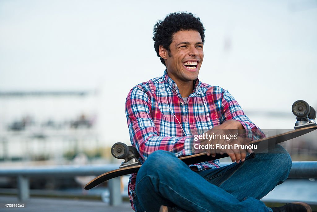 Skateboarder sitting with skateboard on lap