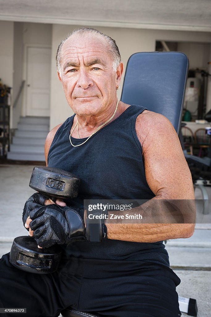 Portrait of muscular senior man holding dumb bells