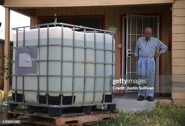 Porterville resident Manuel Dominguez, who has no running water, stands on his porch next to his tank of non-potable water on April 23, 2015 in...