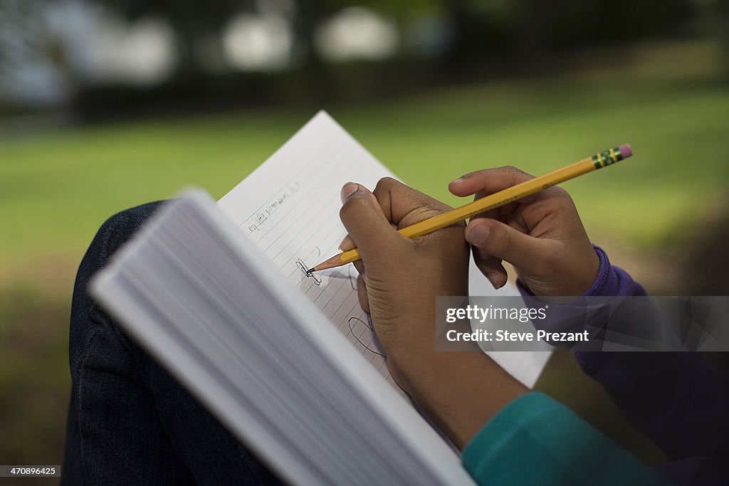 Close up of sisters in park writing in notebook