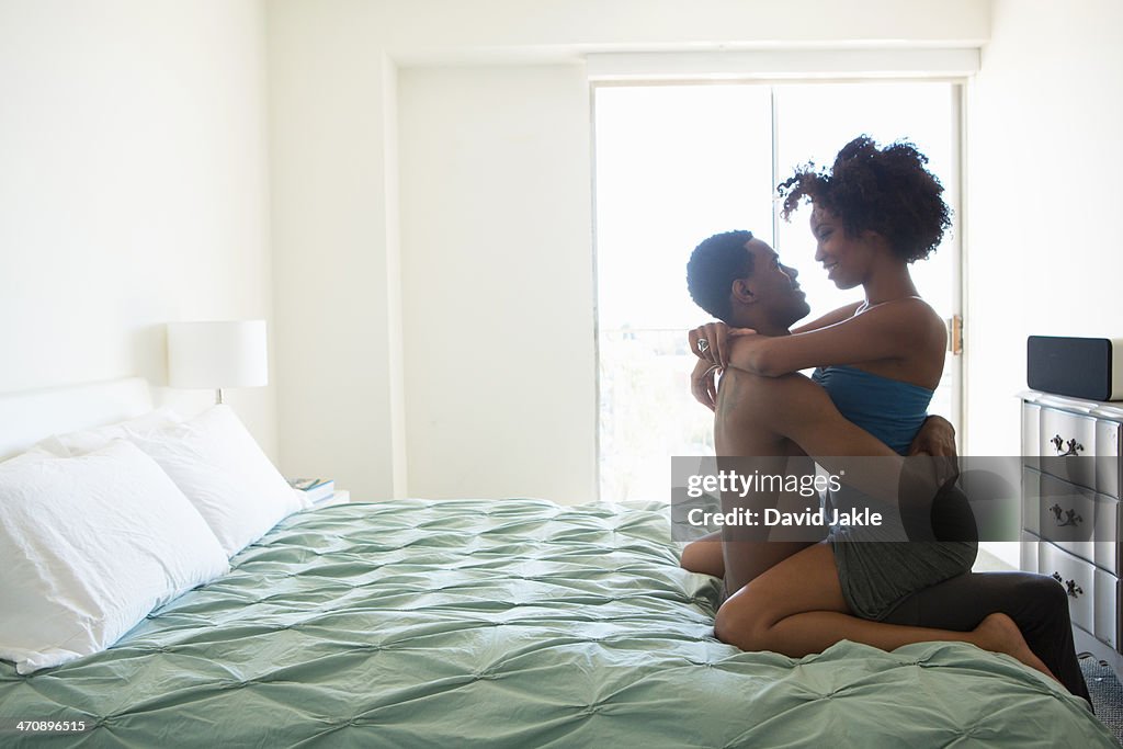 Young woman straddling man on bed