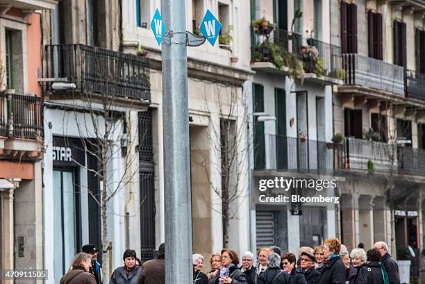 Pedestrians stand beneath a municipal city Wi-Fi signal point on a street in Barcelona, Spain, on Friday, Feb. 21, 2014. A smart city initiative,...
