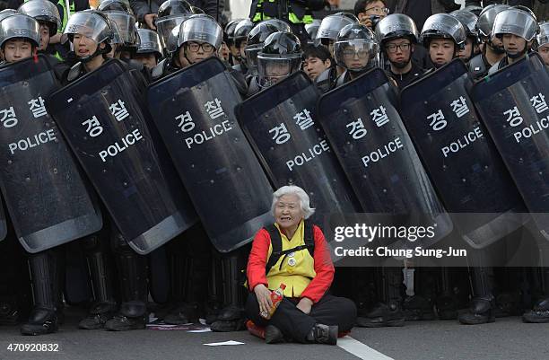 Woman sits in front of riot police blocking the road to protect protesters during the anti-government protest on April 24, 2015 in Seoul, South...