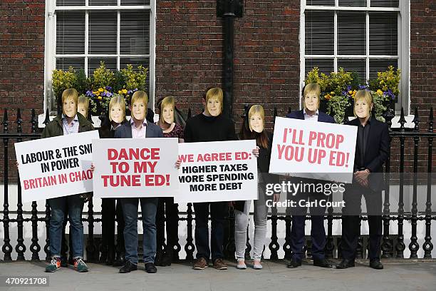 Conservative Party activists, wearing masks bearing the face of SNP leader Nicola Sturgeon, protest ahead of a speech by Labour leader Ed Miliband as...