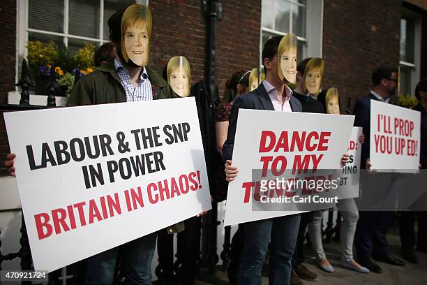 Conservative Party activists, wearing masks bearing the face of SNP leader Nicola Sturgeon, protest ahead of a speech by Labour leader Ed Miliband as...