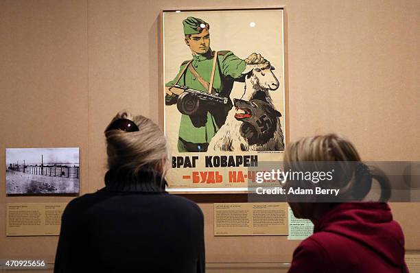 Visitors look at a poster reading 'The enemy is crafty - remain vigilant!' in Russian, featuring a Nazi wolf in sheep's clothing, during a visit to...