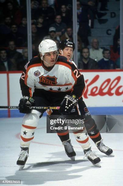 Rick Tocchet of the Wales Conference and the Pittsburgh Penguins skates on ice as he is defended by Phil Housley of the Campbell Conference and the...