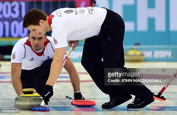 Great Britain's David Murdoch throws the stone as Great Britain's Scott Andrews brushes the ice surface during the Men's Curling Gold Medal Game...