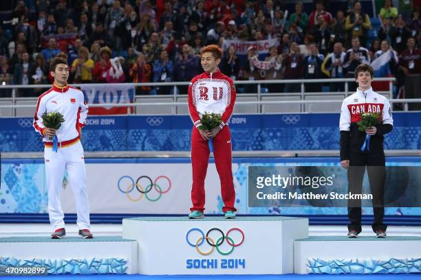 Silver medalist Dajing Wu of China, gold medalist Victor An and bronze medalist Charle Cournoyer of Canada celebrate on the podium during the flower...