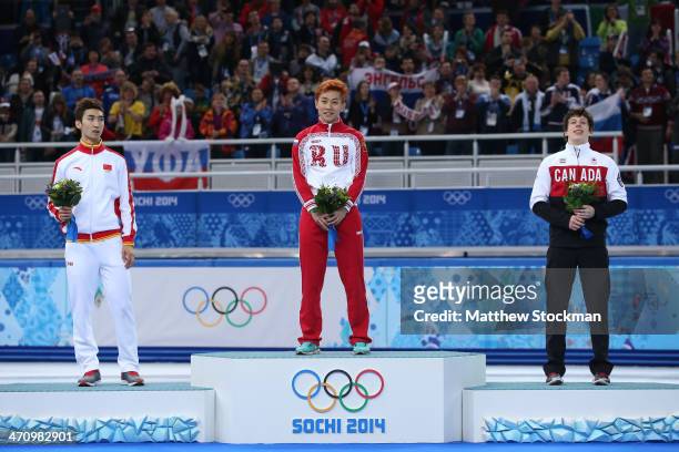 Silver medalist Dajing Wu of China, gold medalist Victor An and bronze medalist Charle Cournoyer of Canada celebrate on the podium during the flower...