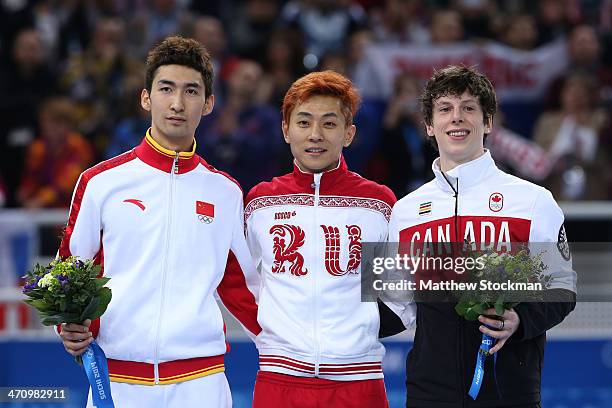 Silver medalist Dajing Wu of China, gold medalist Victor An and bronze medalist Charle Cournoyer of Canada celebrate on the podium during the flower...