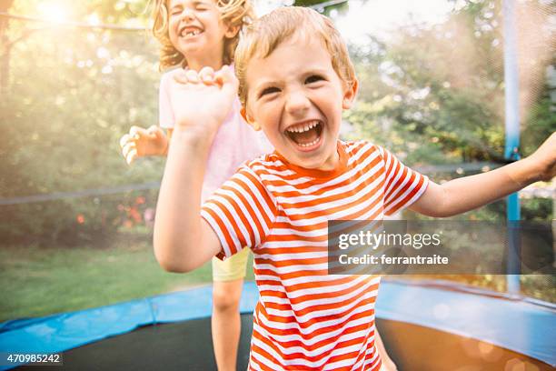children on summer holidays jumping on trampoline - trampolin bildbanksfoton och bilder