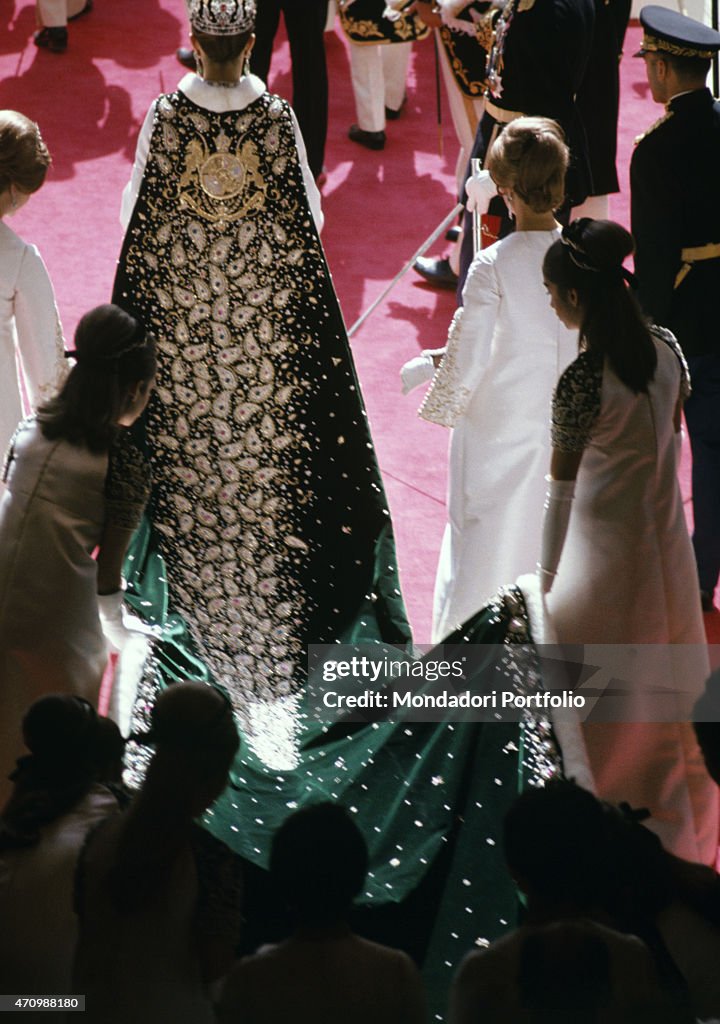 A group of women carry the long wedding trail of the wedding dress of Farah Diba