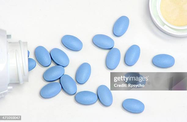 blue pills spilled out from a bottle - viagra stock pictures, royalty-free photos & images