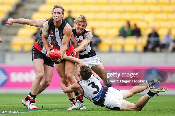 Luke Dunstan of St Kilda handpasses in the tackle of Marc Murphy of Carlton during the round four AFL match between the St Kilda Saints and the...