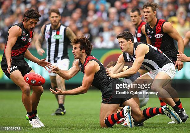 Jobe Watson of the Bombers handballs whilst being tackled by Jack Crisp of the Magpies during the round four AFL match between the Essendon Bombers...