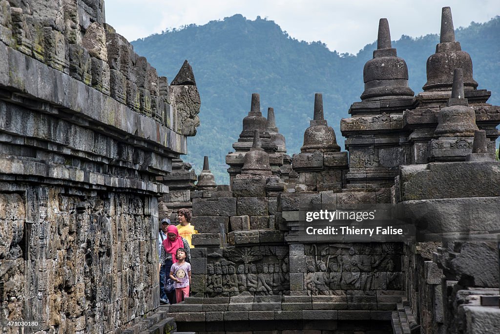 A family of tourists walk through bas-reliefs on a platform...