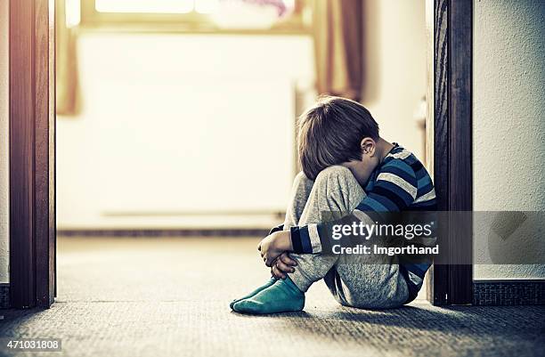 depressed little boy sitting on the floor - arm around stockfoto's en -beelden