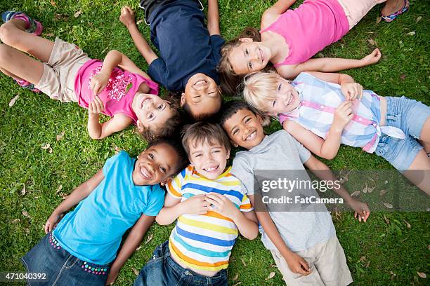 children in grass with heads in circle - kid lying down stock pictures, royalty-free photos & images