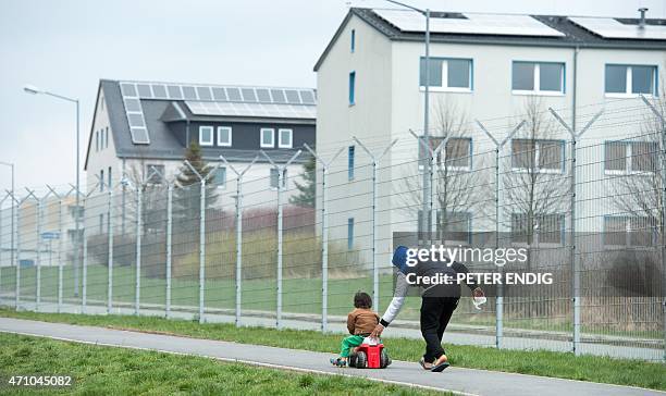 Refugee pushes his son on a bobby-car in a refugee center on April 17, 2015 in Schneeberg, Germany. AFP PHOTO / DPA / PETER ENDIG +++GERMANY OUT